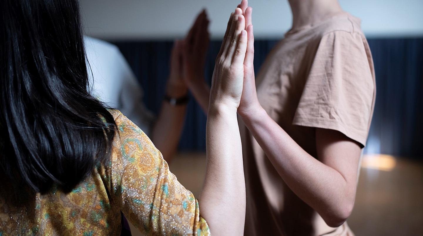 Två personer trycker handflatorna mot varandra.