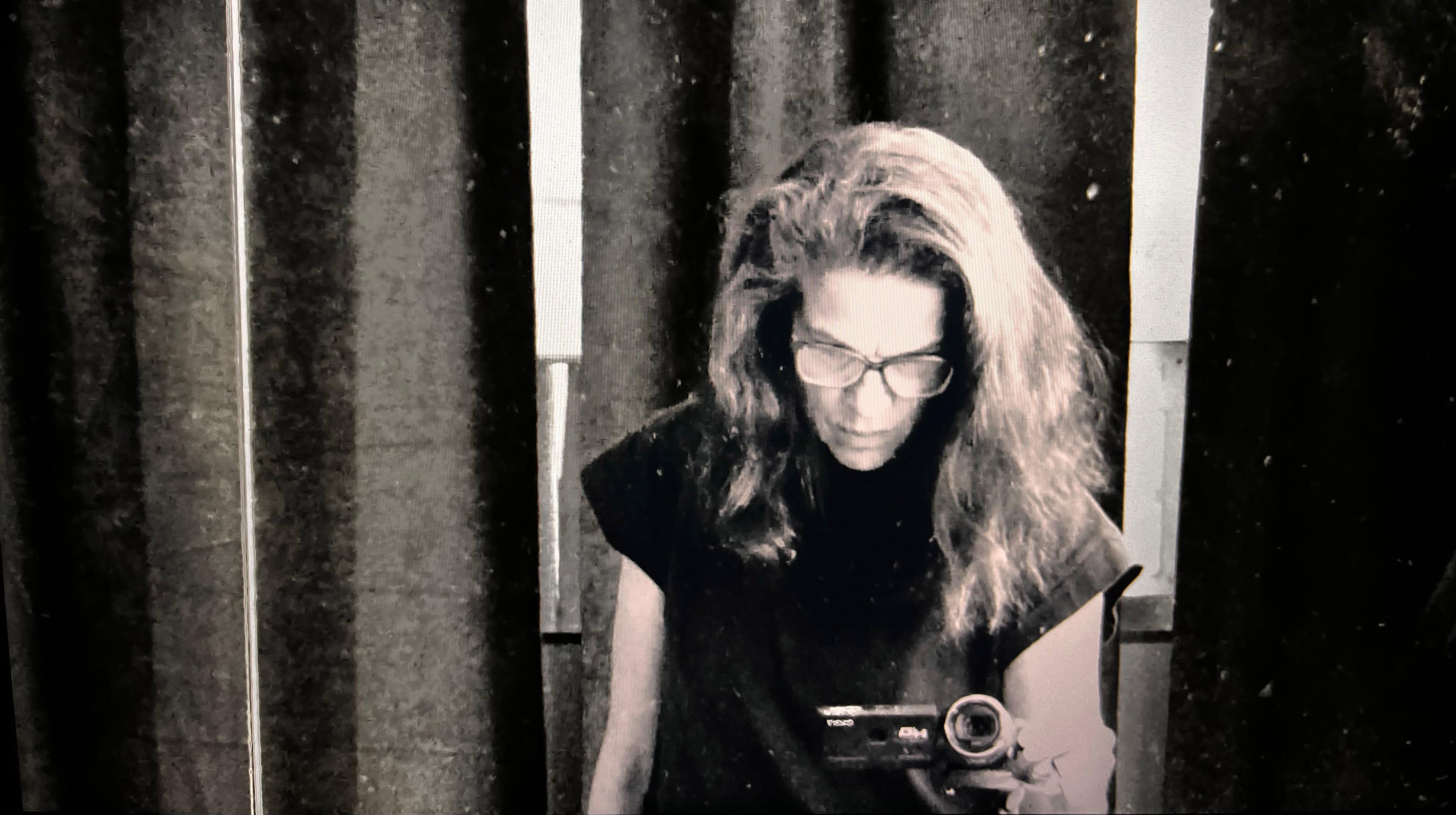 Black and white photo with a person holding a small camera towards you